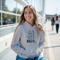 Load image into Gallery viewer, Woman wearing a hoodie with text, sitting outdoors on a sunny day.
