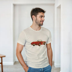Man wearing a beige t-shirt with a red car graphic in a minimalistic room.