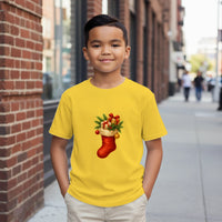 Load image into Gallery viewer, Child wearing a yellow t-shirt with a Christmas stocking design on a city street.
