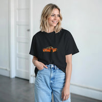 Load image into Gallery viewer, Woman wearing a black t-shirt with a car graphic and light blue jeans indoors.
