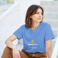 Load image into Gallery viewer, Woman wearing a blue t-shirt with &#39;MINDSET is Everything&#39; text and light bulb graphic.
