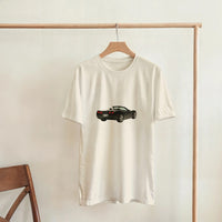 Load image into Gallery viewer, White t-shirt with a black car graphic on a wooden hanger against a white wall.
