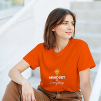 Load image into Gallery viewer, Woman wearing an orange t-shirt with &#39;MINDSET is Everything&#39; text and light bulb graphic.
