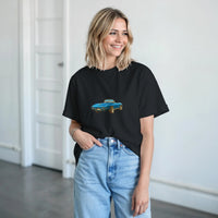 Load image into Gallery viewer, Woman wearing a black t-shirt with a graphic design of a blue car, standing indoors.
