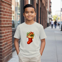 Load image into Gallery viewer, Child wearing a white t-shirt with a Christmas stocking design on a city street.
