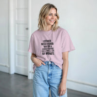 Load image into Gallery viewer, Woman wearing a pink t-shirt with text, standing indoors.
