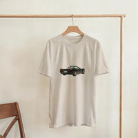 Load image into Gallery viewer, Beige t-shirt with a black car graphic on a wooden hanger against a white wall.
