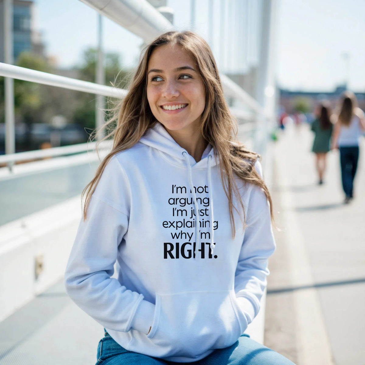Woman wearing a light blue hoodie with text, sitting outdoors on a sunny day.